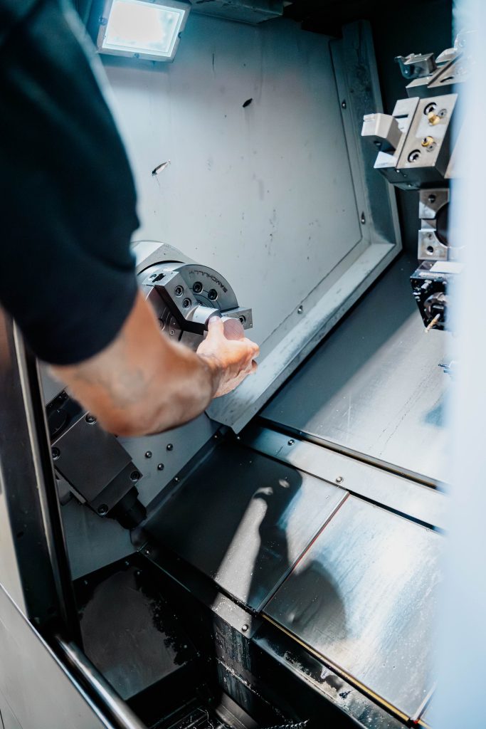 Operatore inserisce pezzo metallico in tornio CNC