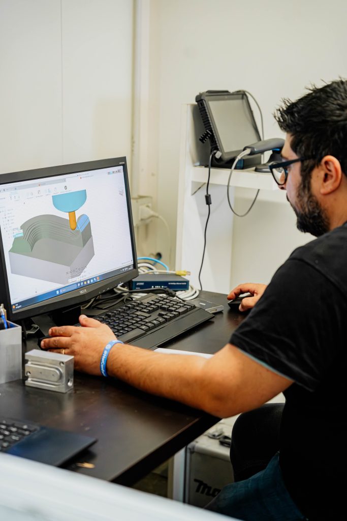 Uomo lavora su progetto CAD per meccanica, visualizzato su schermo